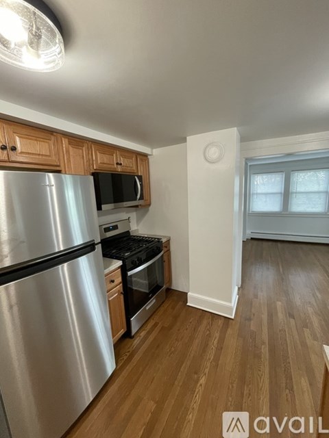 A kitchen with a stainless steel refrigerator and wooden cabinets.