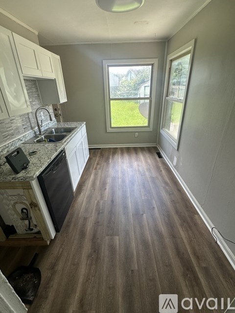 A kitchen with wooden floors and white cabinets.