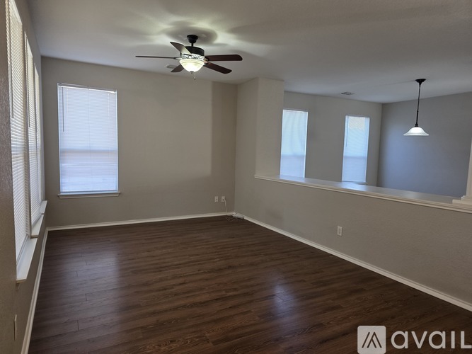A spacious room with a ceiling fan and wooden flooring.