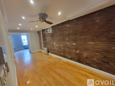A room with wooden floors and a brick wall.
