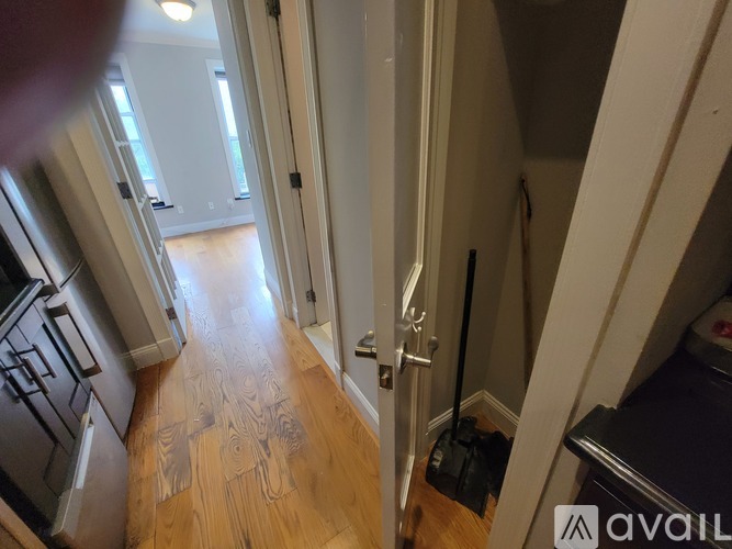 A hallway with a wooden floor and white walls.