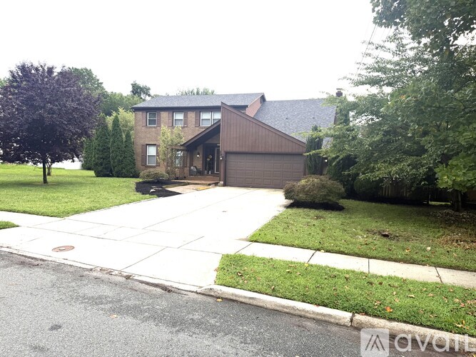 A house with a well-maintained lawn and a sidewalk in front.