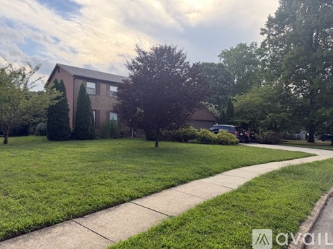 A house with a well-maintained lawn and a sidewalk in front.