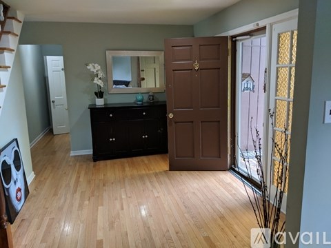 A room with a wooden floor, a brown door, and a mirror on the wall.