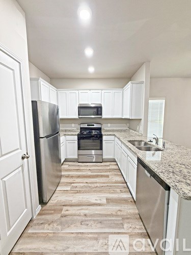 A kitchen with white cabinets and a granite countertop.