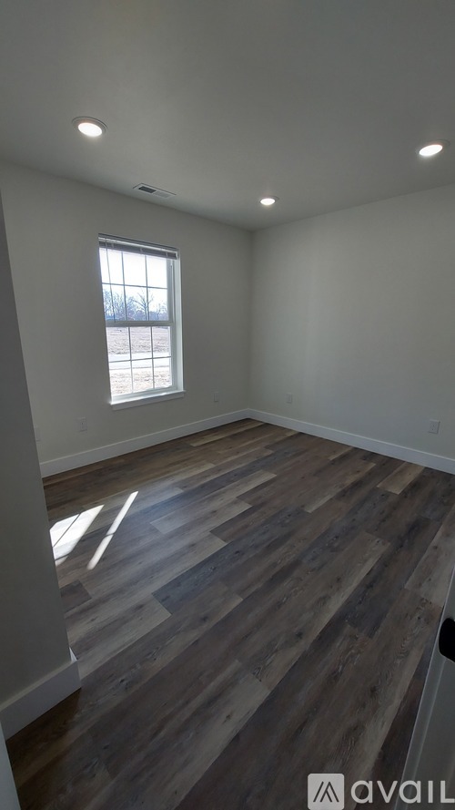 A room with wooden flooring and a window letting in light.
