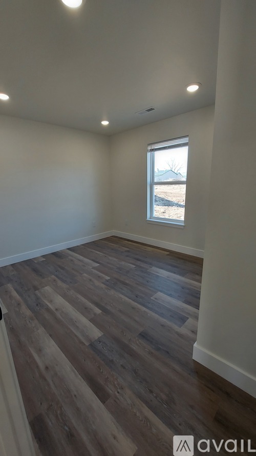 A room with wooden flooring and a window showing a barren landscape outside.
