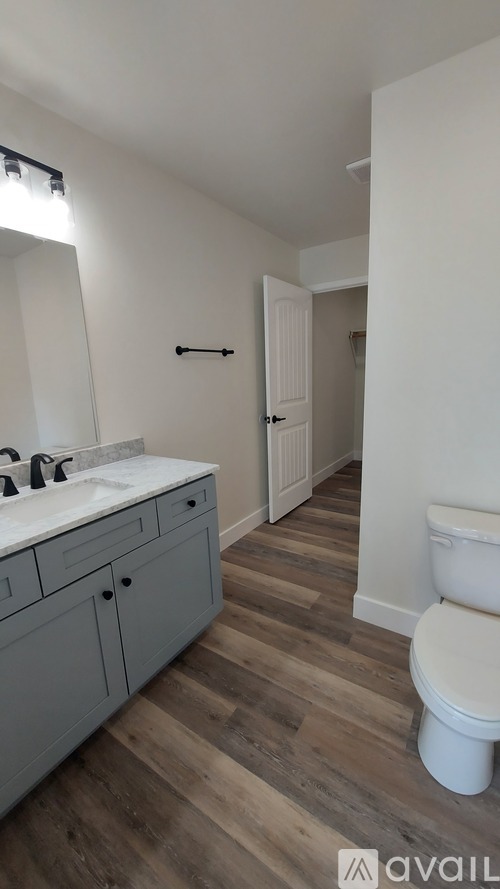A bathroom with a toilet, sink, and cabinets.