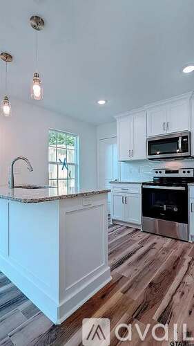 A kitchen with white cabinets and a wooden floor.