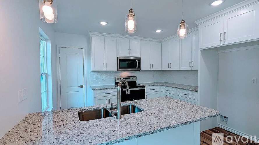A kitchen with granite countertops and white cabinets.