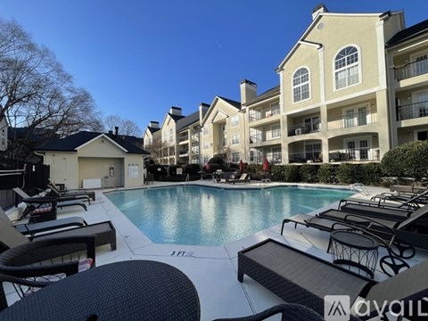 A pool area with lounge chairs and apartment buildings in the background.