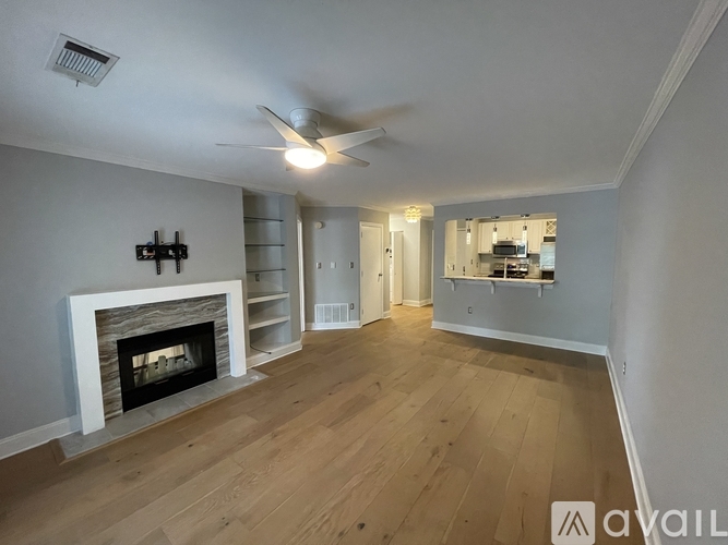 A spacious living room with a fireplace and a ceiling fan.