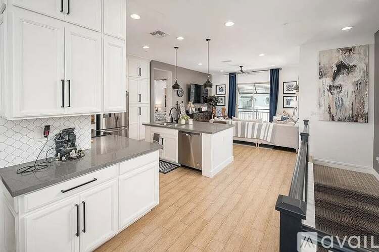 A modern kitchen with white cabinets and a wooden floor.