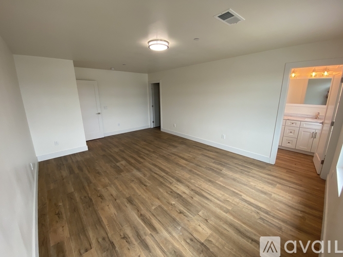 A spacious room with wooden flooring and white walls.