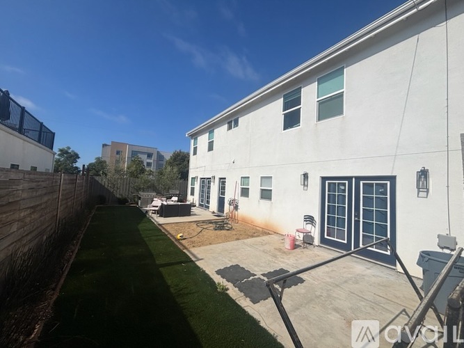 A white building with a black fence and a green lawn in front.