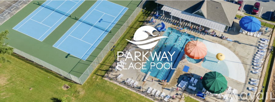 An aerial view of a park with a black pool and tennis courts.