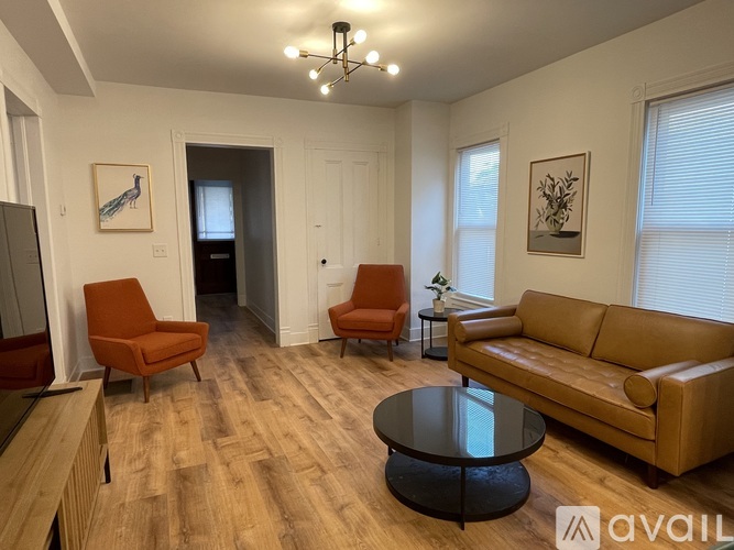 A living room with a brown couch, two chairs, and a coffee table.
