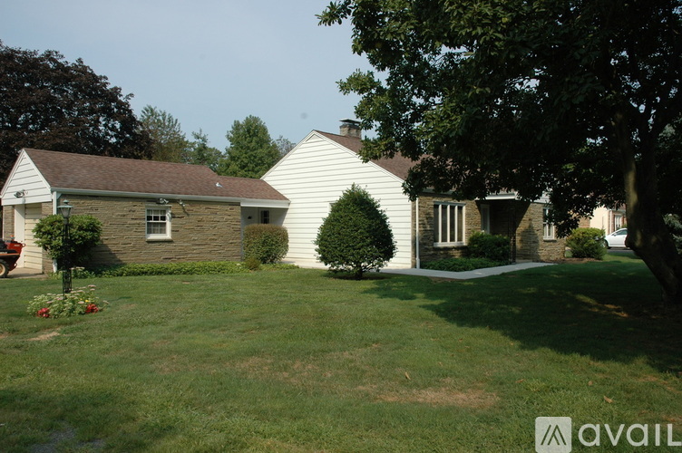 A house with a white exterior and a red flower bed in front.