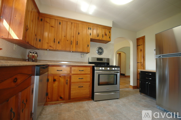 A kitchen with wooden cabinets and a stainless steel refrigerator.