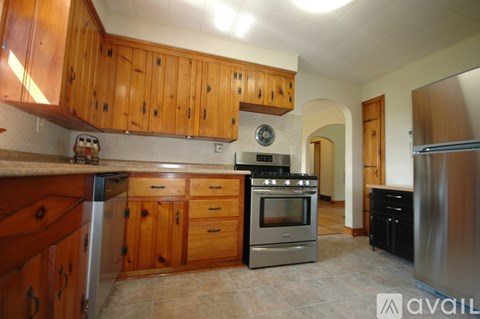 A kitchen with wooden cabinets and a stainless steel refrigerator.