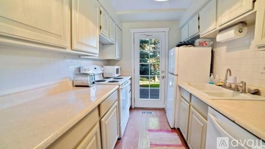 A kitchen with white cabinets and a white fridge.
