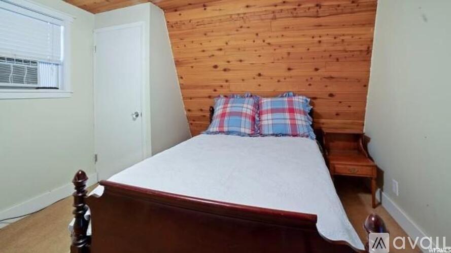 A bedroom with a bed, wooden headboard, and a window.