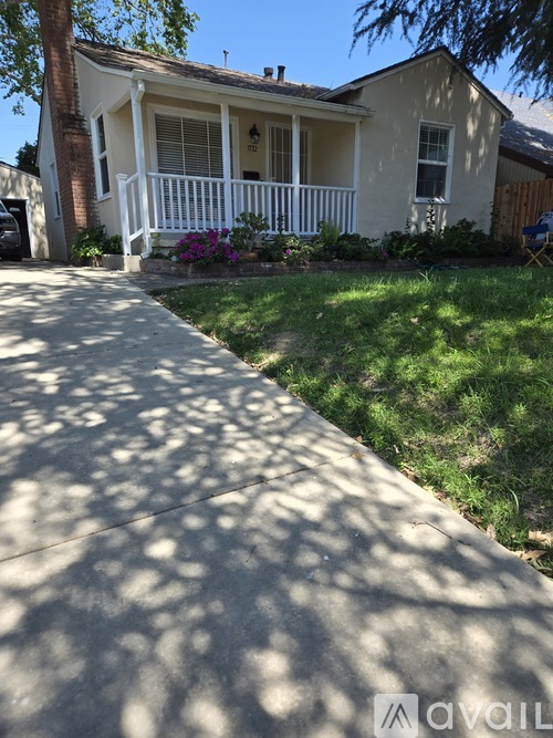 A house with a white porch and a tree in front.