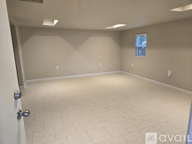 A spacious room with tiled flooring and a window with blinds.