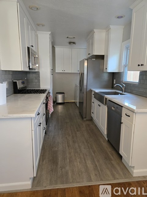 A kitchen with white cabinets and a grey floor.