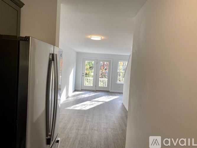 A kitchen with a refrigerator on the left and a view of a deck through a glass door.