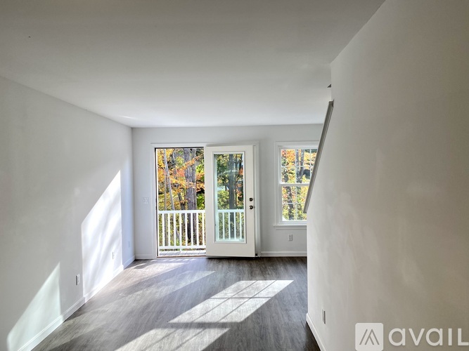 A spacious room with a view of a deck and trees through the windows.