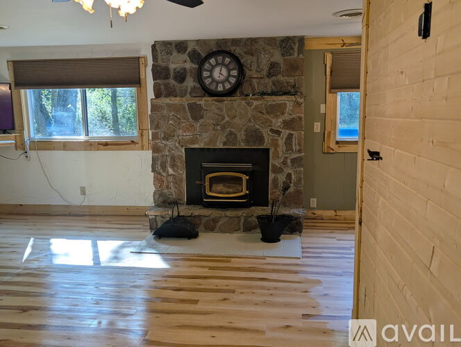 A room with a stone fireplace and a ceiling fan.