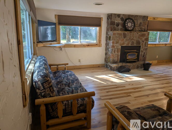 A living room with a stone fireplace and a flat screen TV mounted above it.