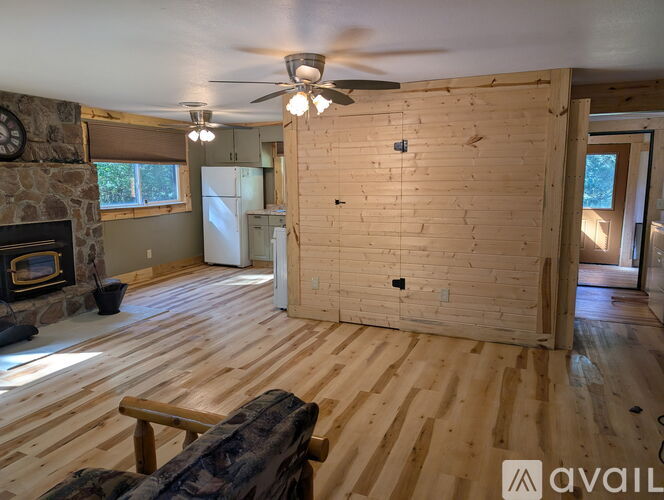 A living room with wooden floors and a stone fireplace.