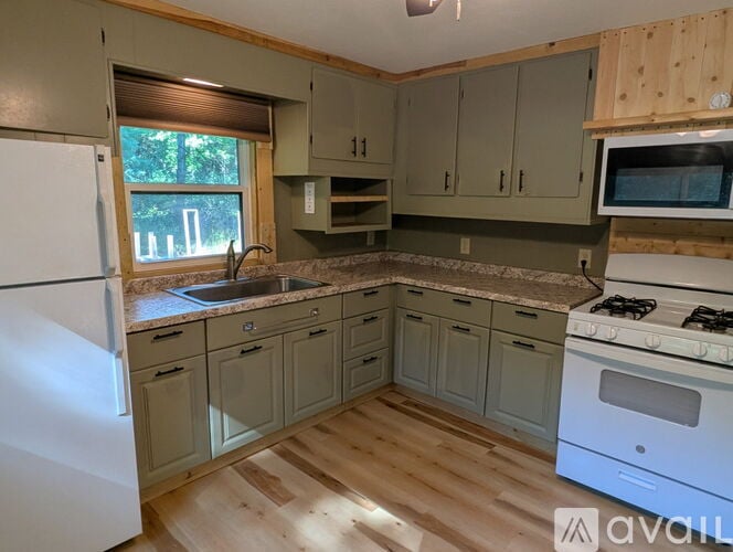 A kitchen with wooden floors and a white stove top oven.