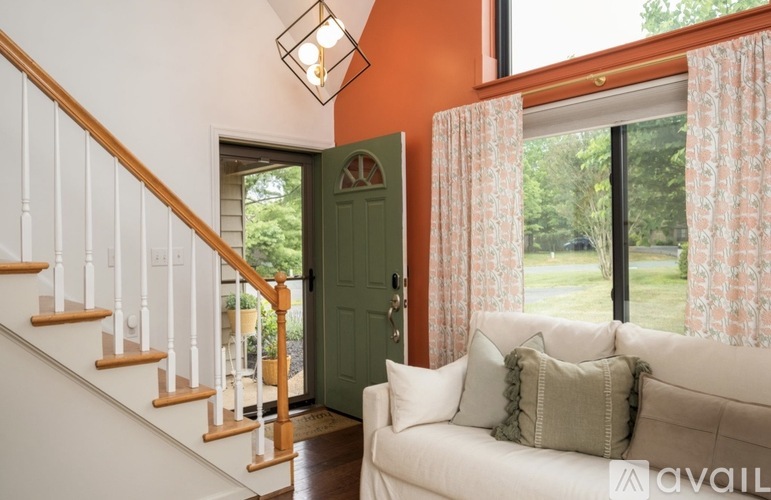 A living room with a white couch and a green door.