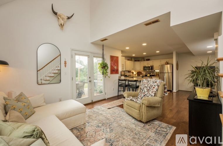 A living room with a white couch and a cow skull on the wall.