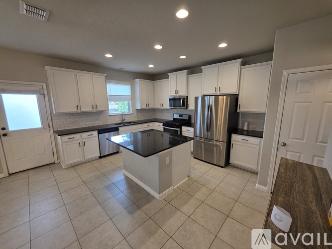 A kitchen with white cabinets and a black countertop.