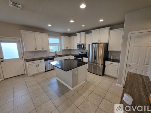 A kitchen with white cabinets and a black countertop.