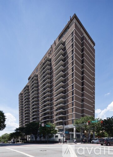 A tall building with many windows is located on a street corner.
