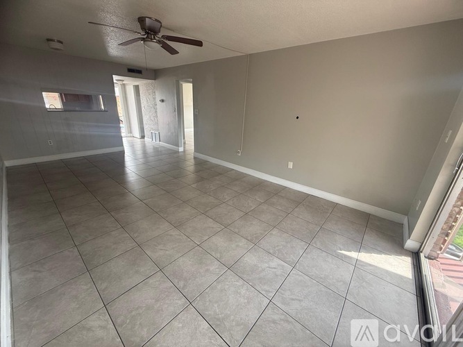 A spacious room with a ceiling fan and tile flooring.