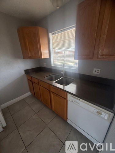 A kitchen with wooden cabinets and a white dishwasher.