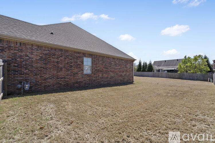 A brick building with a brown roof and a fence in front of it.