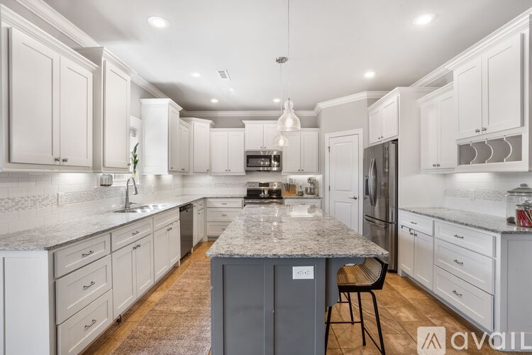 A kitchen with white cabinets and a marble island.