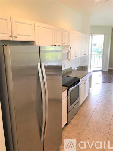 A kitchen with a stainless steel refrigerator and white cabinets.