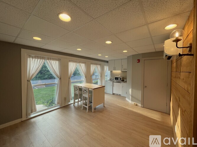 A spacious room with a kitchen area and a dining table with chairs.