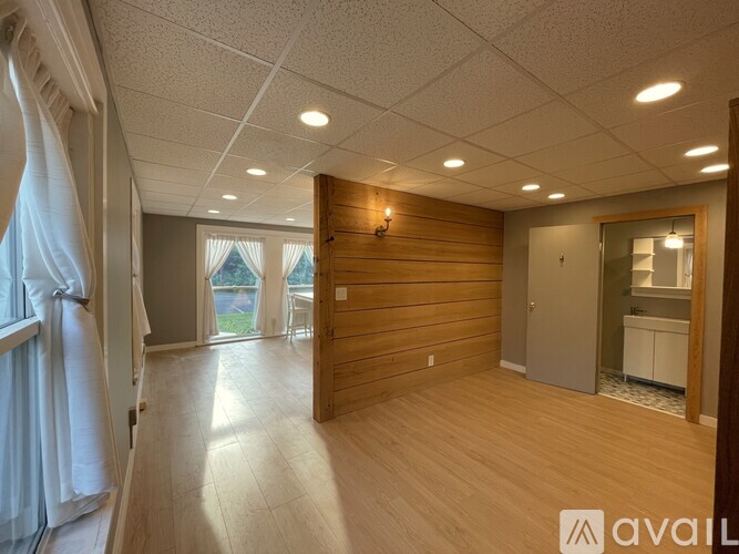 A room with wooden floors and a large window with curtains.