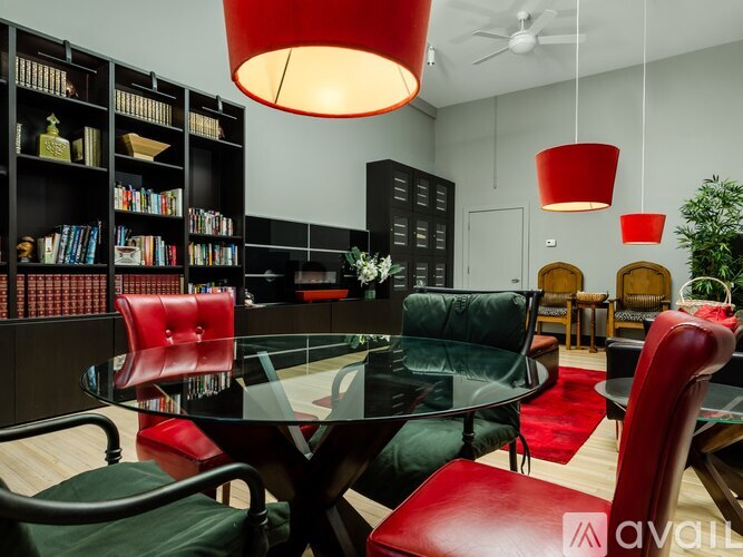 A modern living room with a glass table and red chairs.