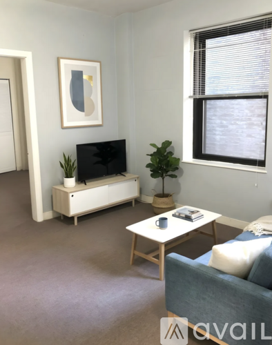 A living room with a grey couch, a white coffee table, a black television, and a framed picture on the wall.