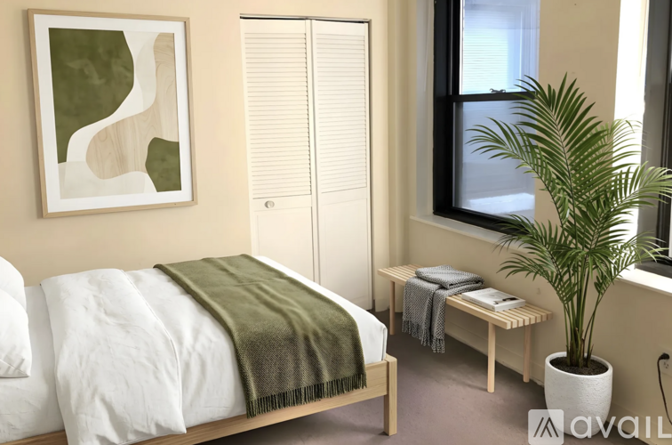 A bedroom with a bed, a bench, and a plant.